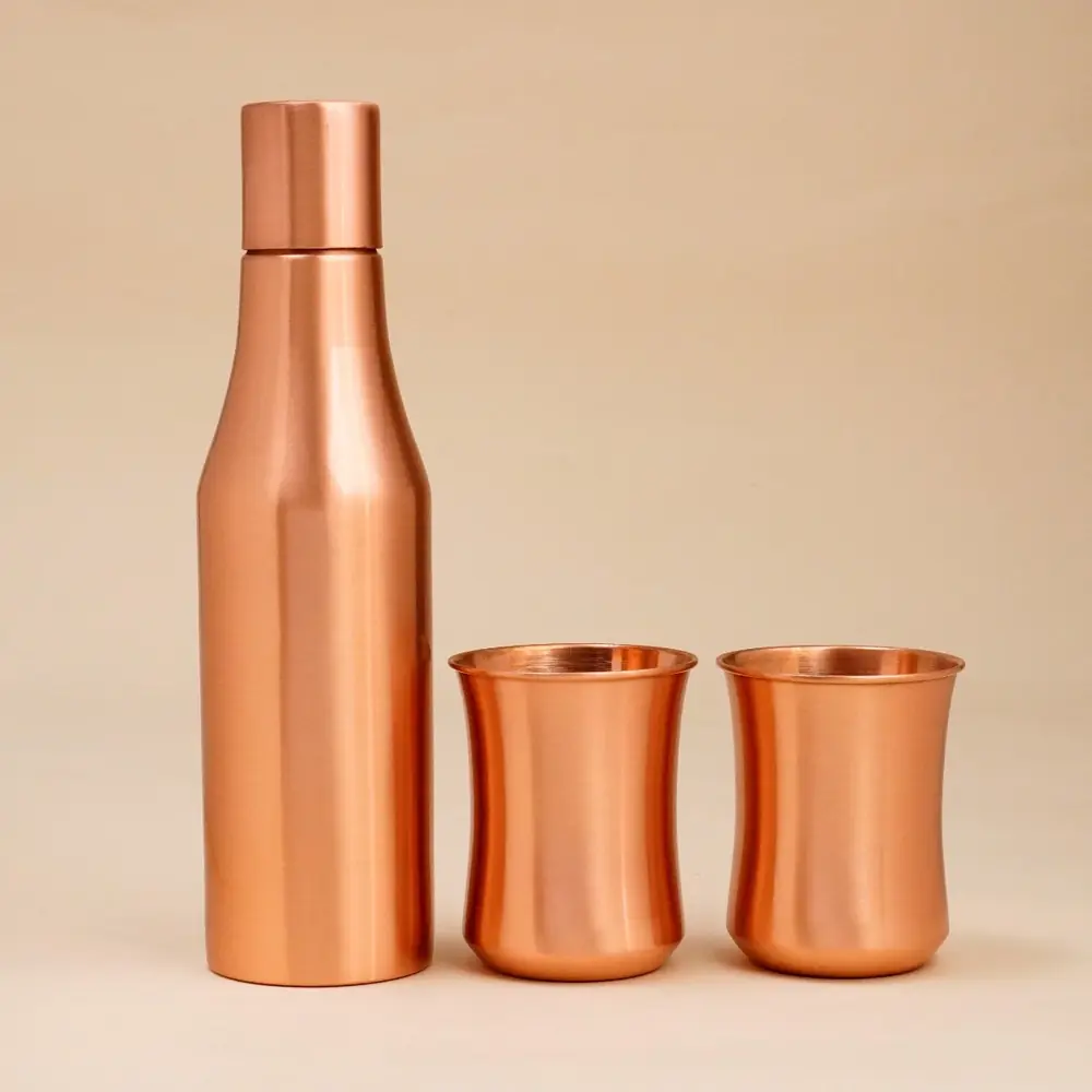 Copper bottle with two glasses on a plain ground