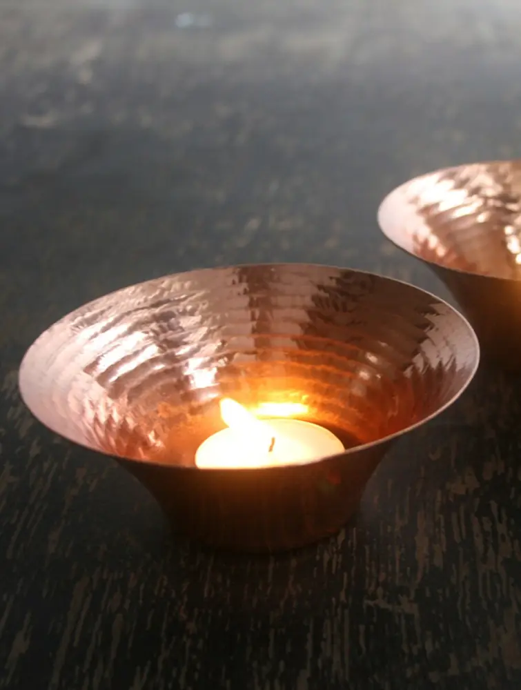 Several copper bowls on a dark table
