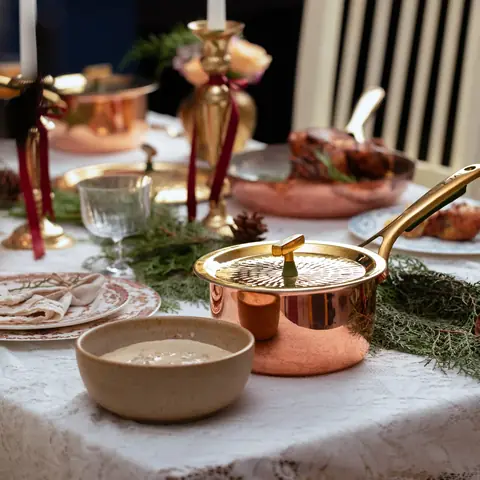 The saucepan in a table scene with bread and bowls