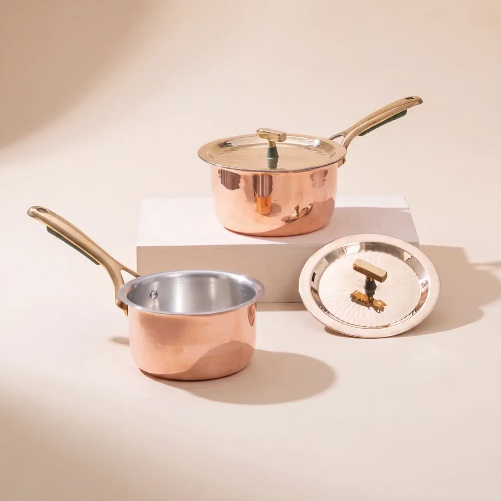 Two copper saucepans with lids and brass coloured handles