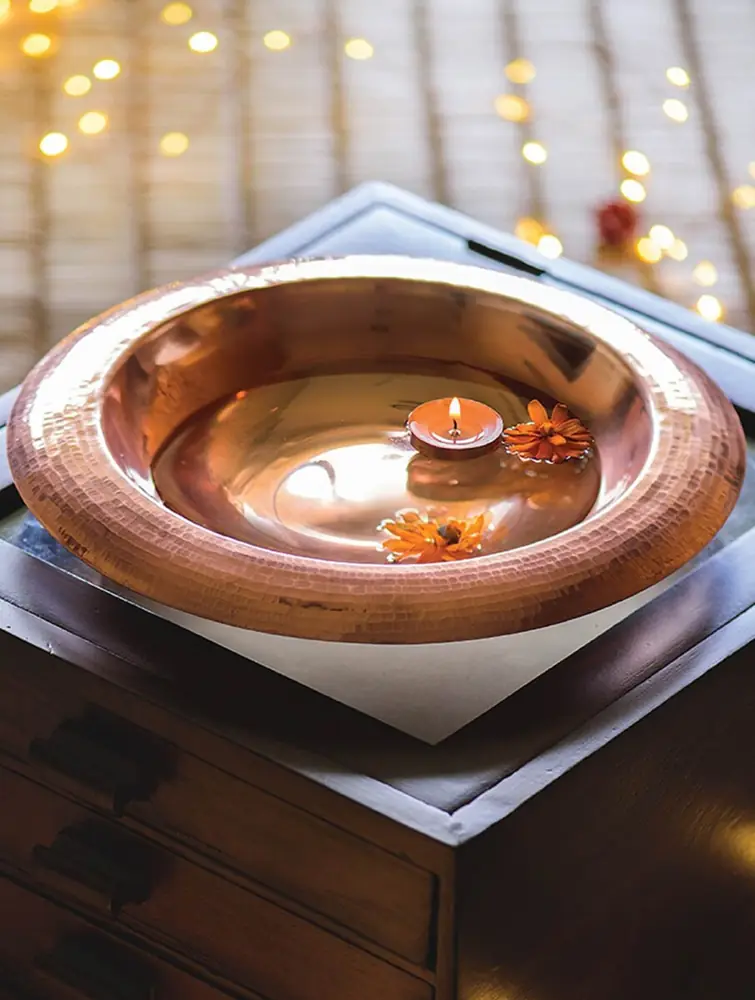 Copper urli with a lit lamp and warm lights behind