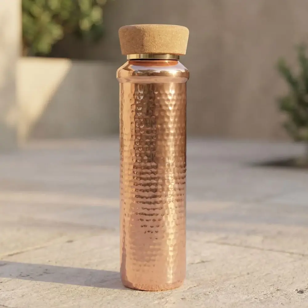 Hammered copper bottle with a cork cap on a stone ledge