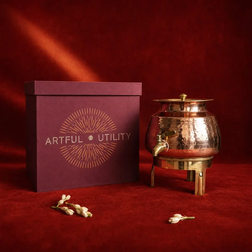 Copper water dispenser beside its dark red gift box