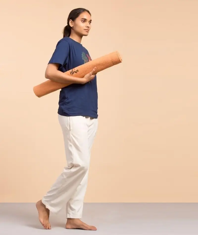 Person carrying a rolled orange cotton rug yoga mat