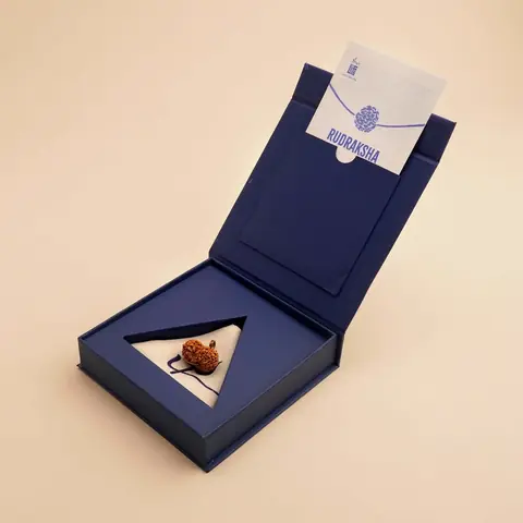 Open blue gift box holding the bead and a card