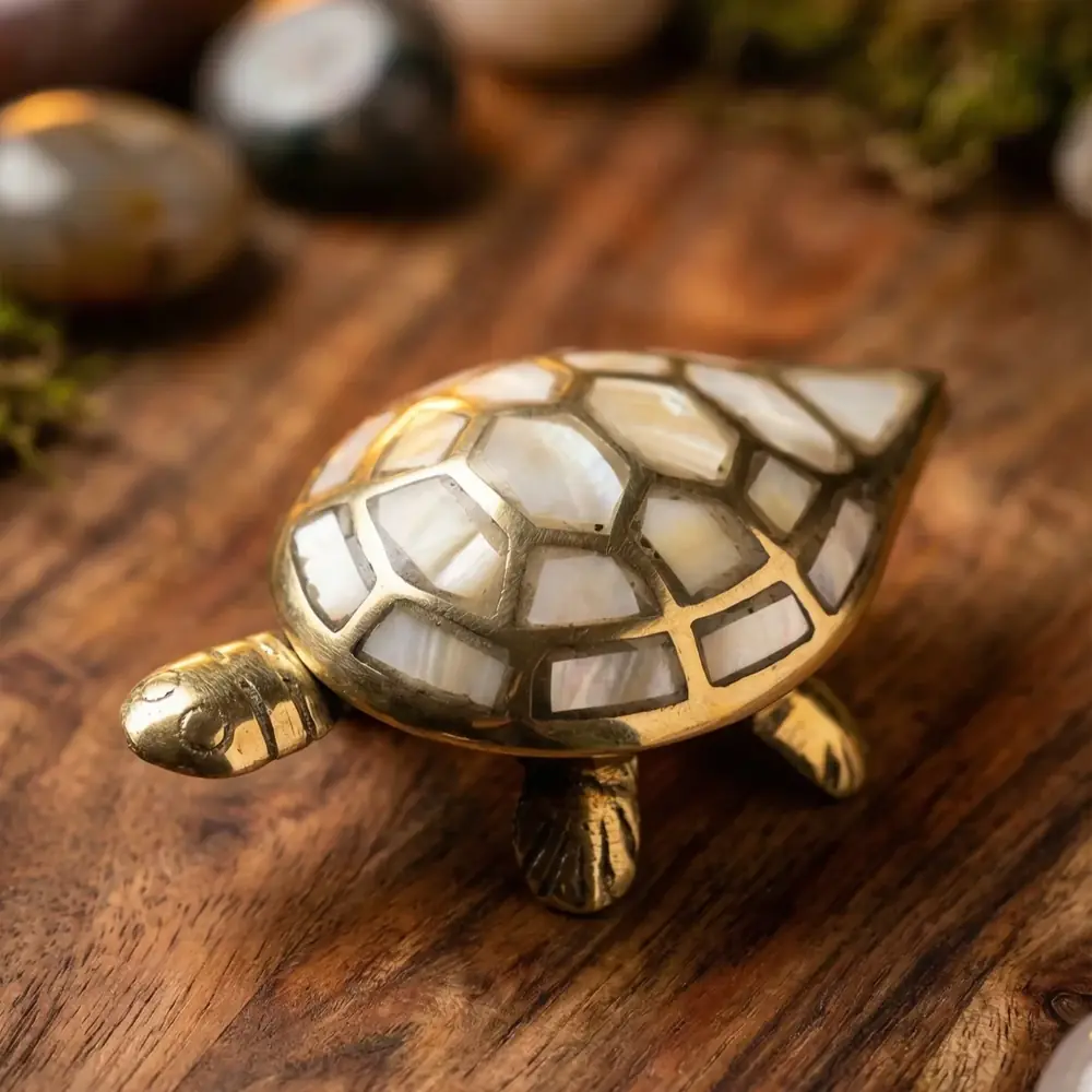 Brass turtle with a pearl mosaic shell on a wooden surface