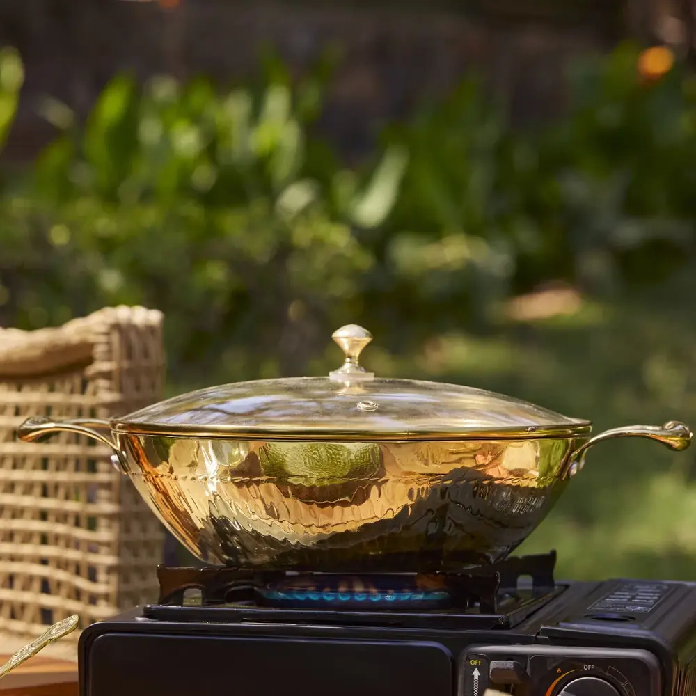The kadhai on a burner outdoors with a lid on