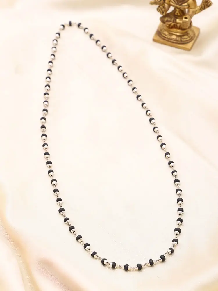 The mala on a cream cloth beside a small brass figure