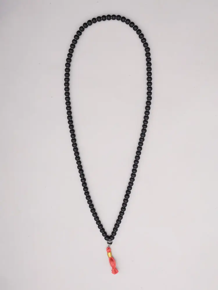 Black ebony japa mala laid out with its orange tassel