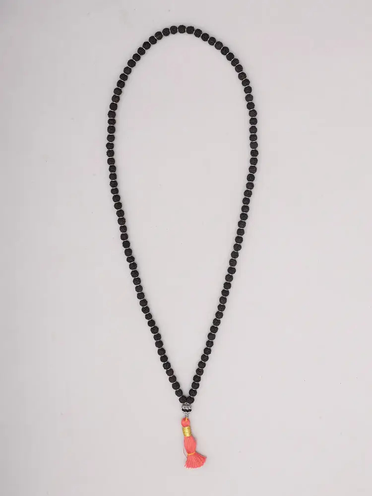 Dark rudraksha mala with an orange tassel laid on a plain ground