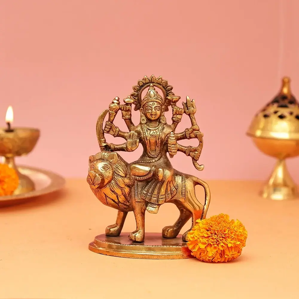 Brass Durga seated on a lion against a peach ground