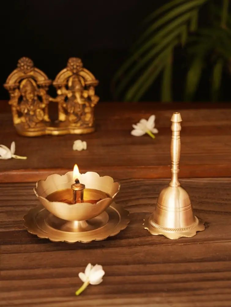Brass lotus lamp holder and bell with idols behind
