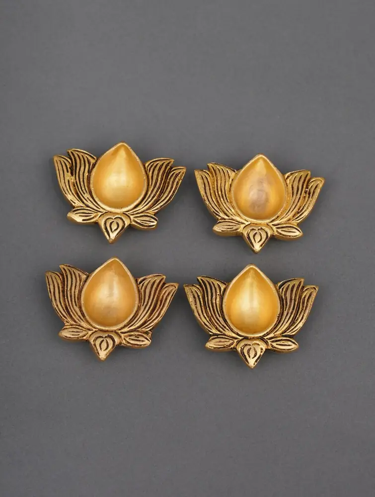 Four brass lotus diyas on red cloth with a lit flame