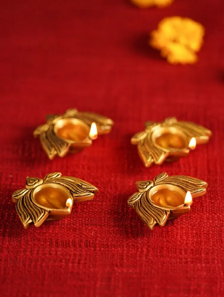 Brass lotus diyas on a grey ground, seen from above