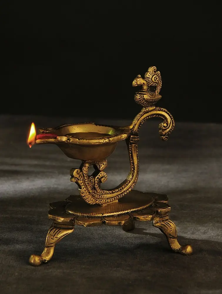 Lit brass lamp on a footed stand with a bird-head stem