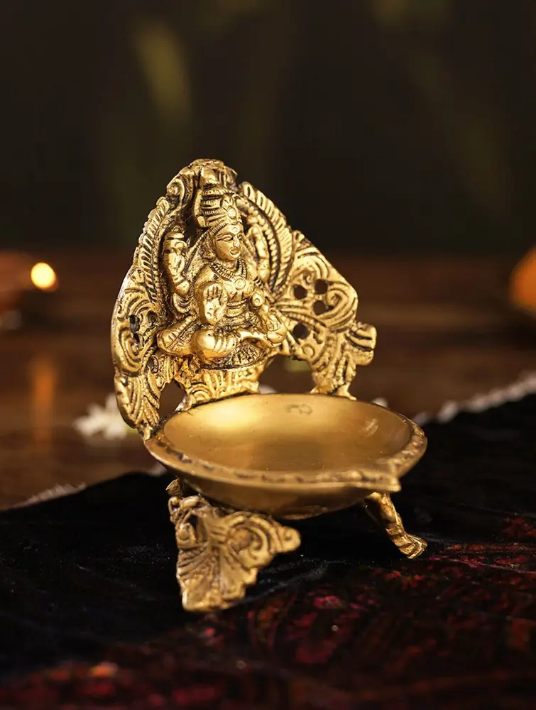 One brass lamp with a carved figure and an oil bowl