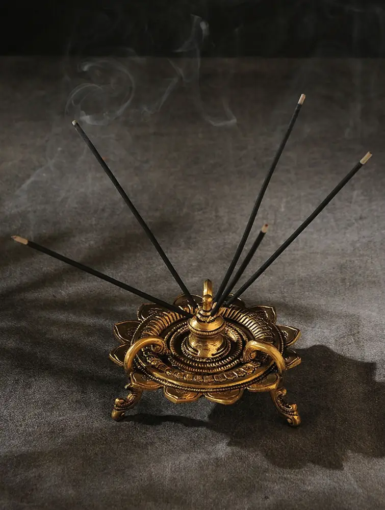 Brass stand with incense sticks standing in it