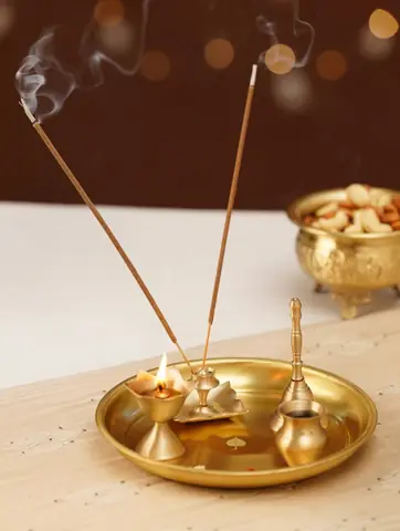 Thali with burning incense sticks and a small brass bowl beside it