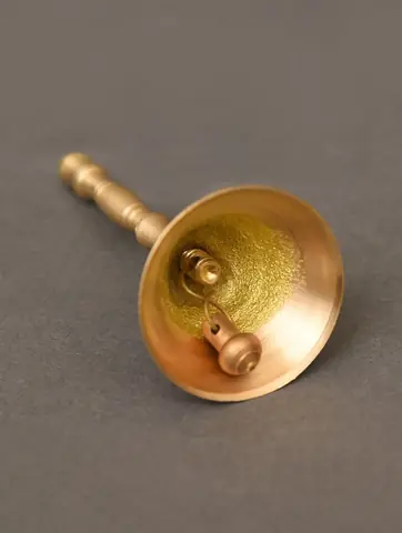A brass hand bell with a short handle