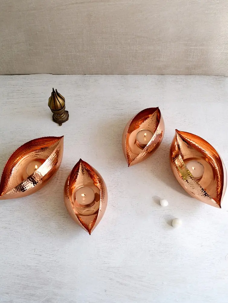 Four leaf-shaped copper holders with tea lights