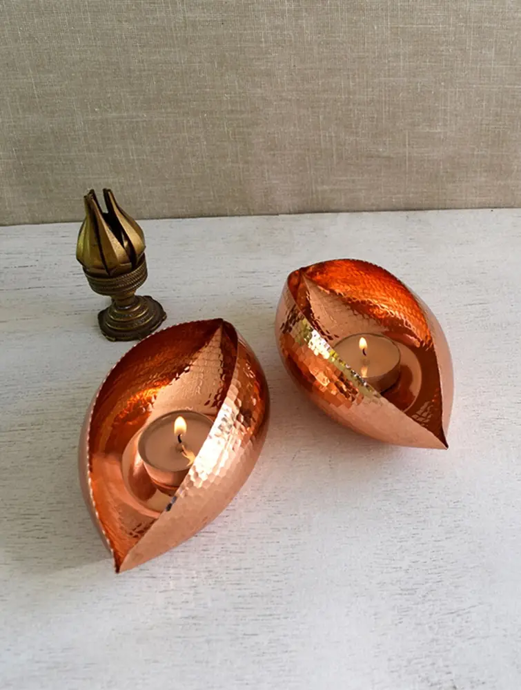 Two polished copper leaf holders on a pale ground