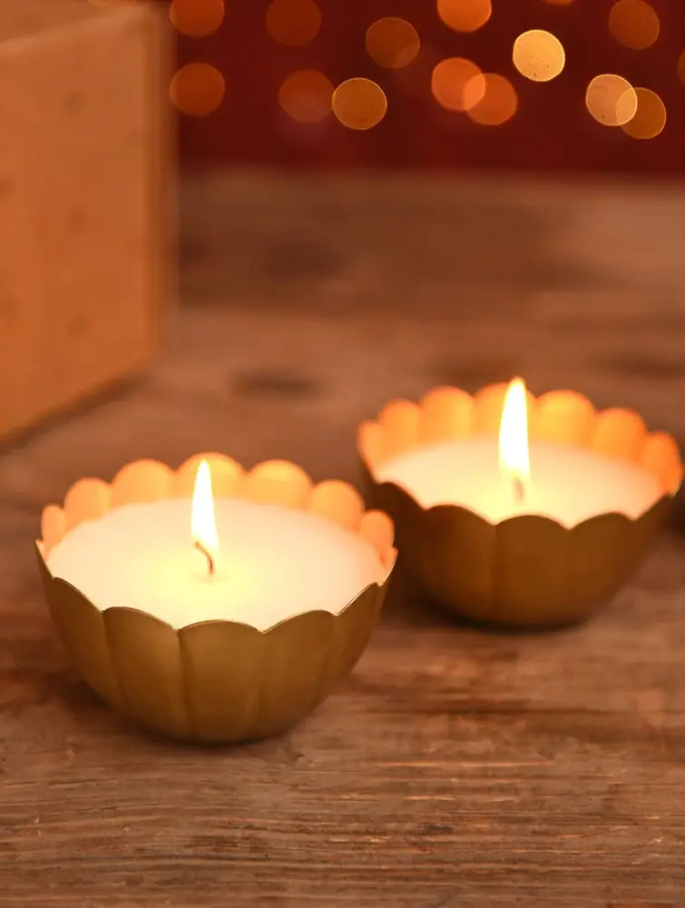 Two lit tea lights in gold-coloured scalloped bowls