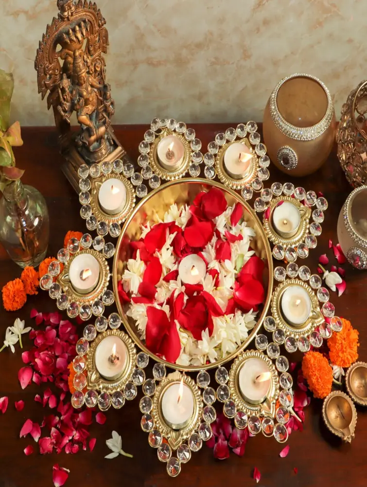 Urli with red petals and lit tea lights on a festival table