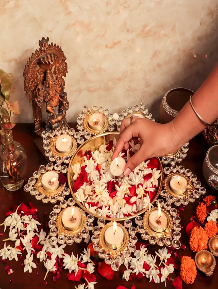 Hand placing flowers around the urli