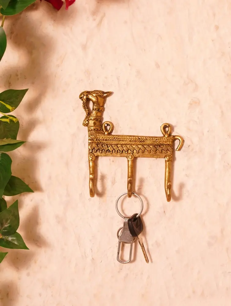 Brass animal hook rack on a pale wall with keys hanging