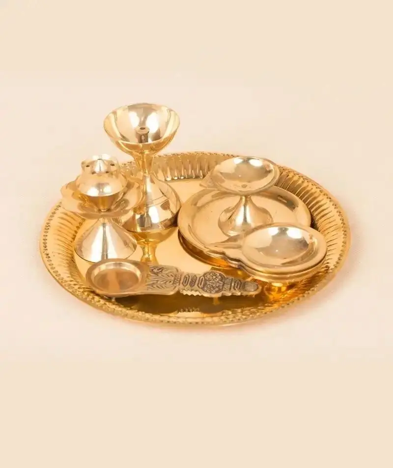 Brass Guru pooja set with lamps and stands arranged on a plate