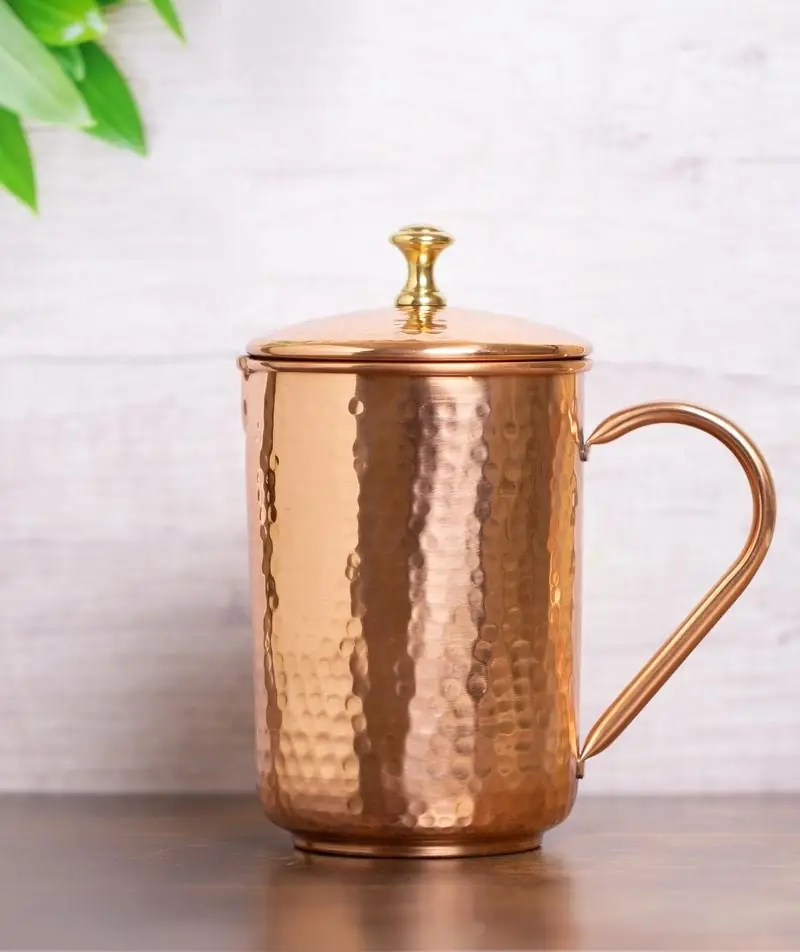 The copper jug on a grey table in front of a wall