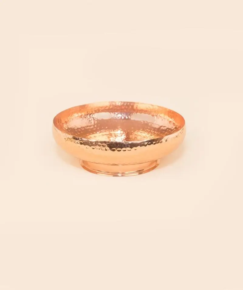 Copper uruli front view on a plain peach background