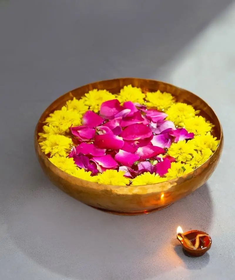Bowl filled with floating flower petals beside a lamp