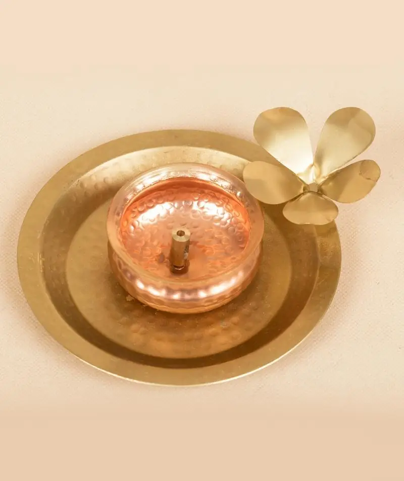 Copper-toned cup on a brass-coloured plate with a flower