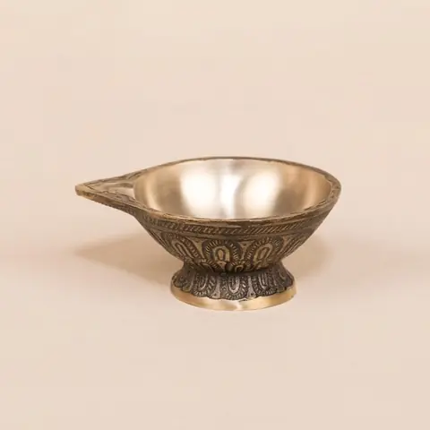 Brass diya seen from the side with its pointed lip