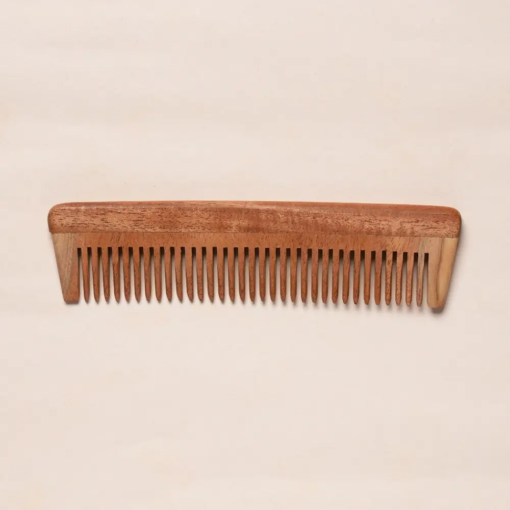 Neem wood comb with fine teeth on a plain background