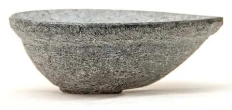 A second view of the grey stone diya on a pale ground