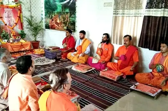 Priests seated on the floor before Hanuman images