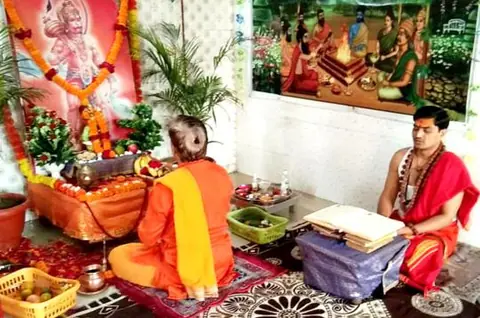 Priests performing a ritual in a room with a Hanuman picture
