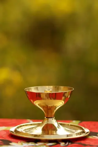 The brass diya on its plate with the cover removed