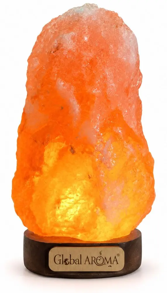 Lit orange salt lamp on a dark round base, on white