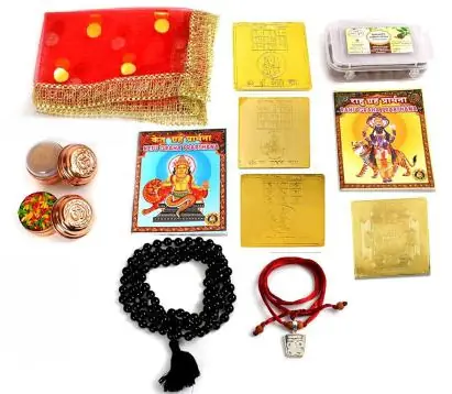 The kit's contents laid out on white: yantras, mala, book and puja items