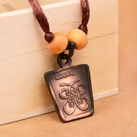 The yantra side on a brown cord with two beads