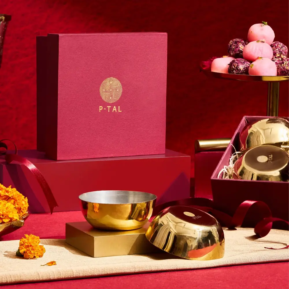 Gold bowls beside a red gift box on a red cloth