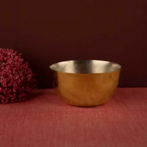 A single golden bowl on a dark red ground