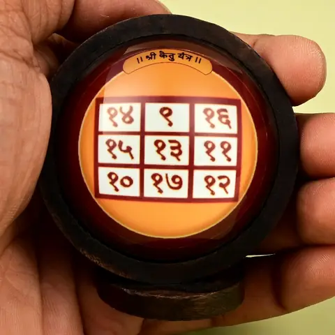 The framed yantra held in a hand for scale