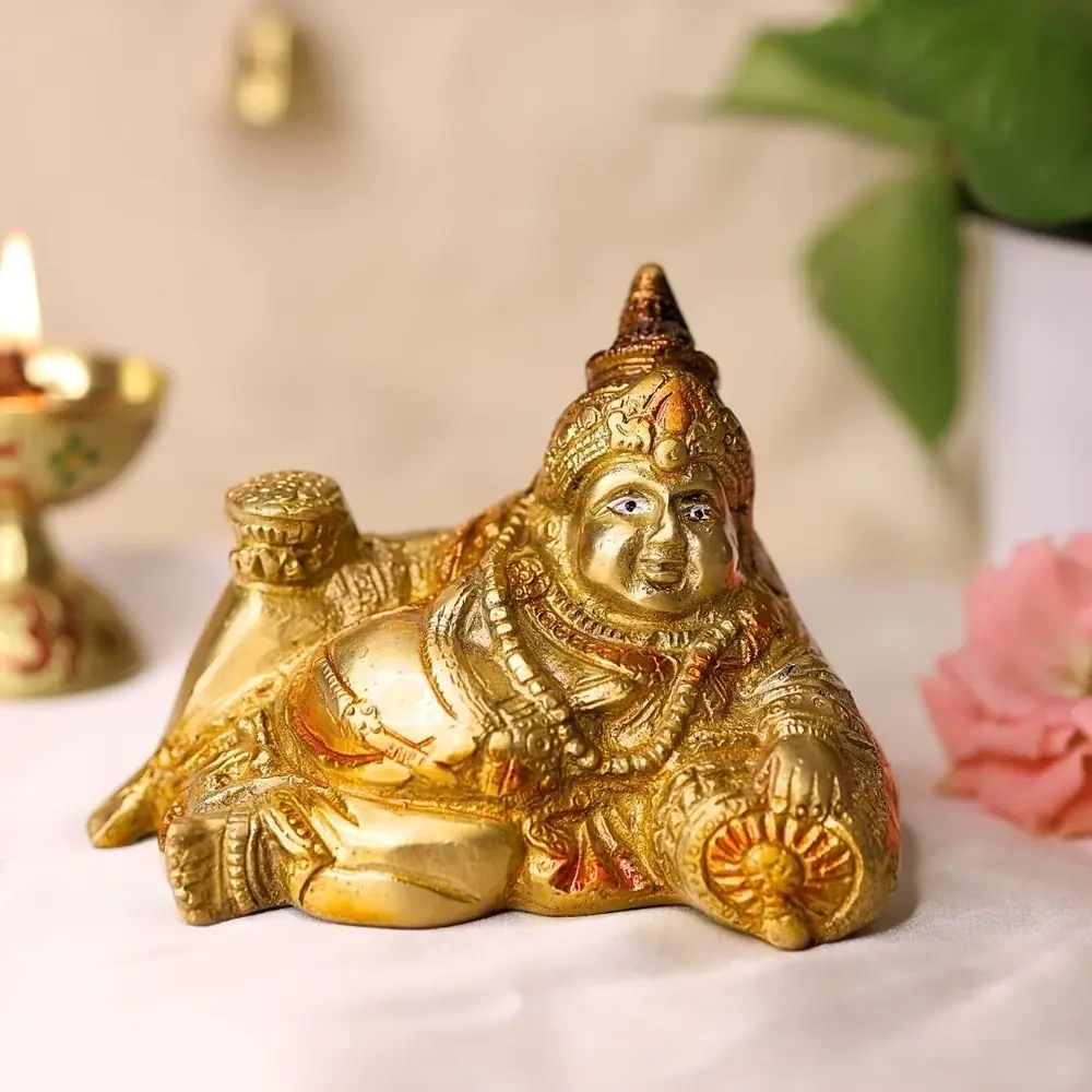 Reclining brass Kubera idol on a white ground