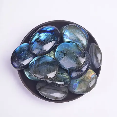 Several polished labradorite stones in a dark dish