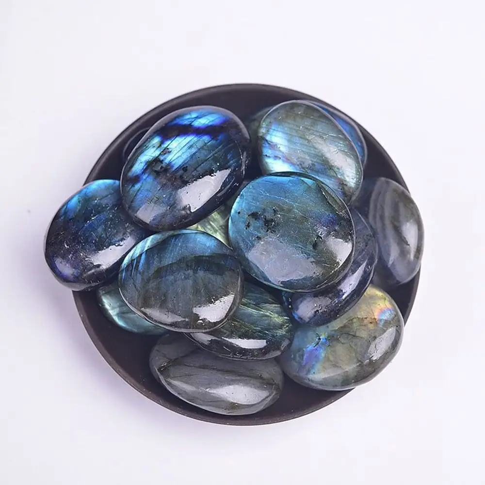 Several polished labradorite stones in a dark dish