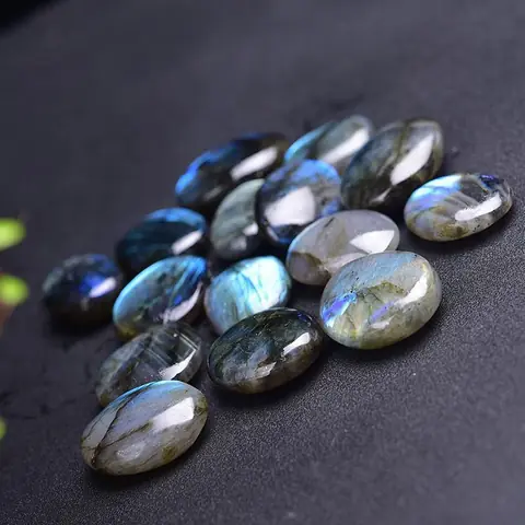 A heap of tumbled labradorite stones on a dark cloth